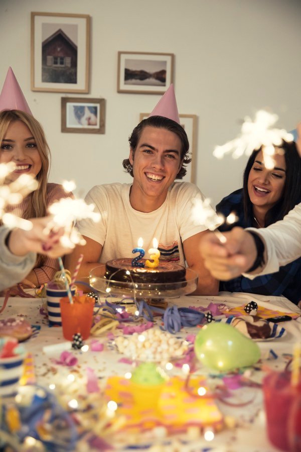 Amigos celebrando un cumpleaños con pastel y luces de bengala — inspiración para invitación digital