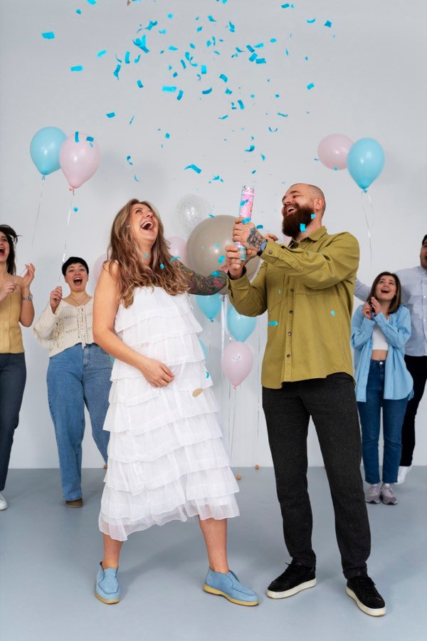 Pareja celebrando una revelación de género con confeti azul — inspiración para invitación digital