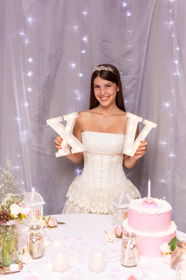 Quinceañera sosteniendo letras luminosas XV — inspiración para invitación digital